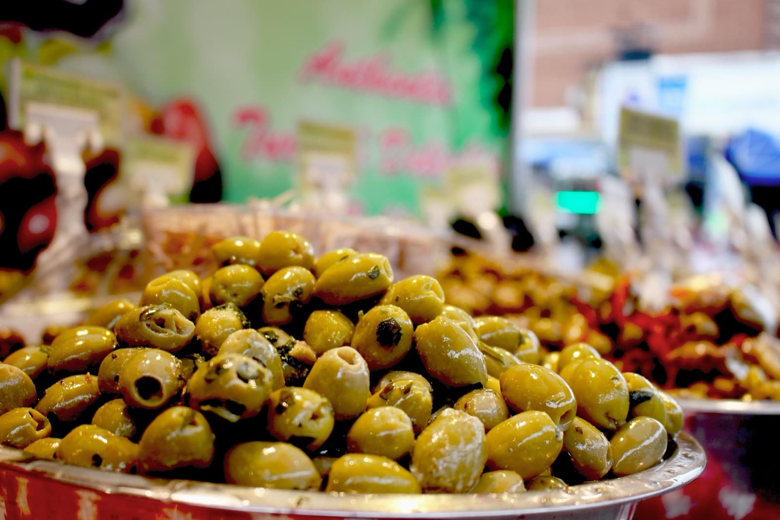 Olive verdi condite, un pilastro della dieta mediterranea Olive verdi condite con erbe aromatiche su un banco del mercato, un classico della dieta mediterranea